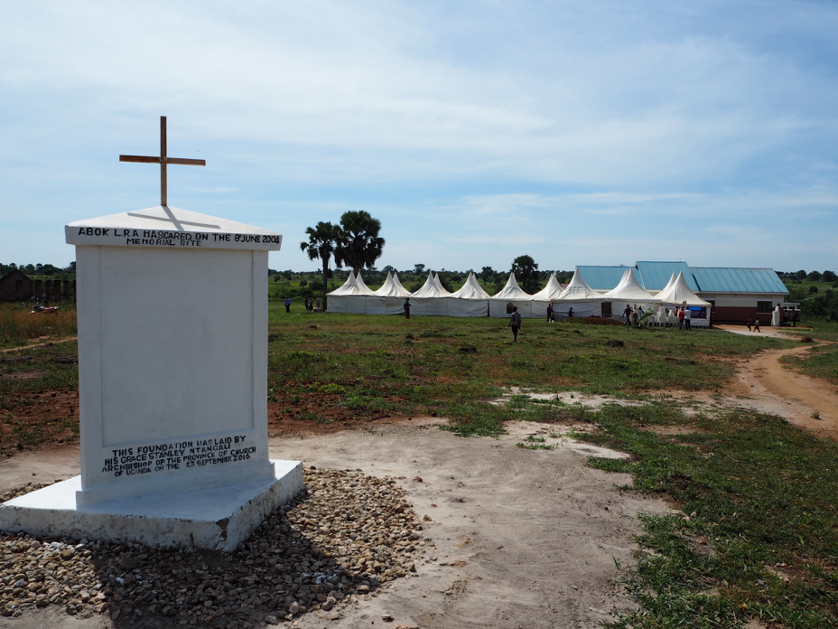 The massacre memorial in Abok, Northern Uganda. In the background: the tents for the public screening of the Ongwen trial (image: Jonas Bens).